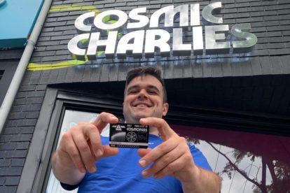 Sean Kady stands in front of Cosmic Charlies holding a loyalty card